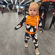 Xayna is registered to the contest to win money with this photo: toddler, child, person, walking, clothing, orange, black, ghost_pattern, shoes, hair, indoors, store, aisle, floor, pacifier, curious, cute, young, portrait, baby
