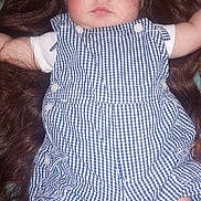 Vaylen-Stone is registered to the contest to win money with this photo: arms_outstretched, baby, blanket, blue_checkered_outfit, buttoned_clothing, child, cute, fabric, face, floral_pattern, indoors, infant, legs_bent, long_hair, lying_down, playful, portrait, skin, soft_lighting, wig