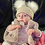 baby, child, hat, pom_poms, fur_vest, blanket, stars, clothing, sitting, indoors, cute, portrait, infant, warm, soft_texture, face, expression, hands, cozy, comfort