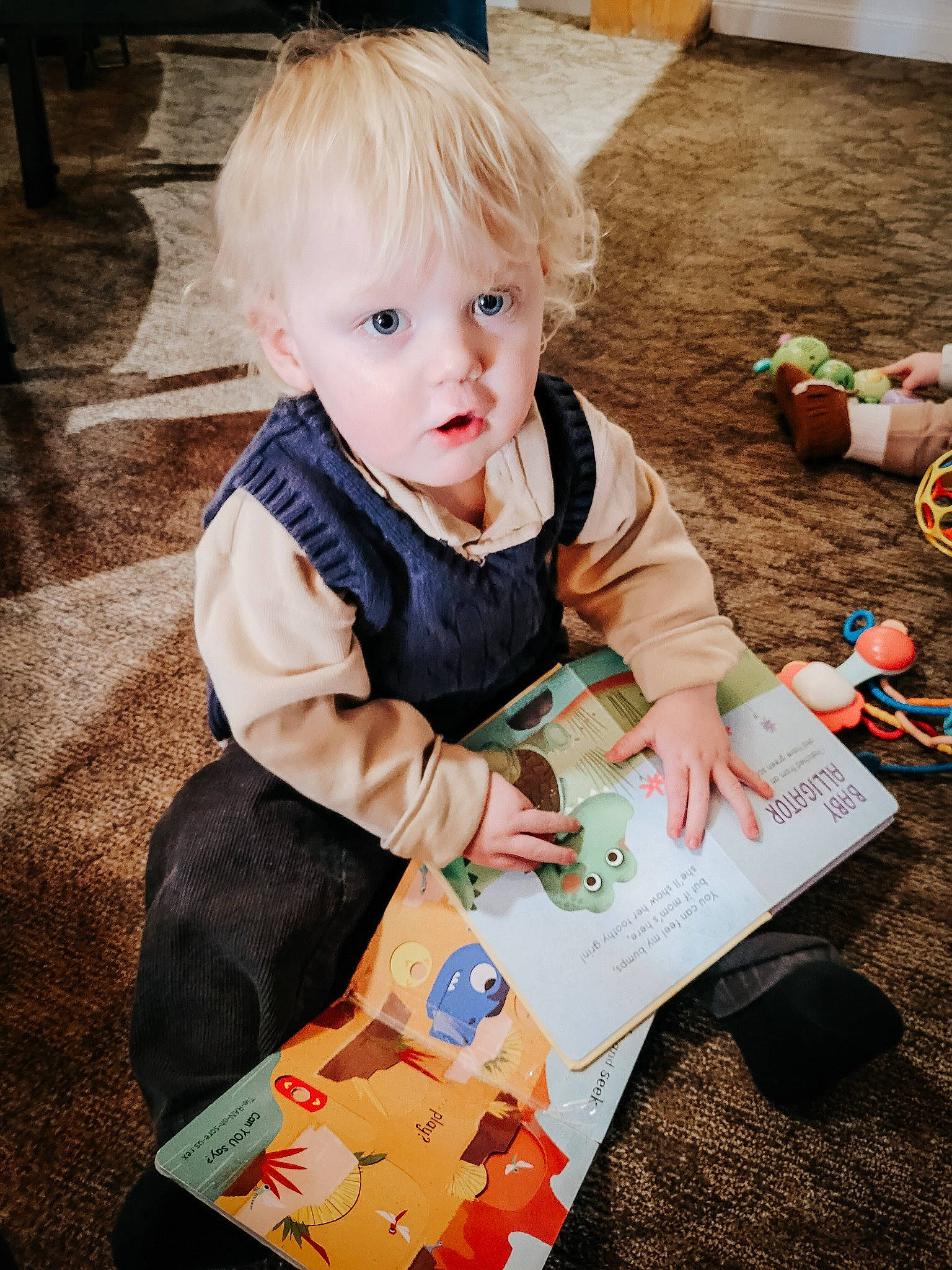 Liam joined the competition — help win amazing prizes! baby, baby_products, baby_toddler_clothing, book, child, dress, flooring, fun, grass, happy, leisure, person, play, reading, recreation, sitting, toddler, wood, writing