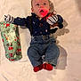baby, infant, clothing, jeans, shirt, suspenders, stuffed_toy, reindeer, gift_wrap, blanket, embroidery, red_light, expression, holiday, christmas, lying_down, cute, child, portrait, indoors