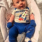 Everett is registered to the contest to win money with this photo: baby, infant, child, blue_clothing, mittens, socks, rocket_ship, onesie, baby_lounger, blanket, plush, patterned, cute, portrait, smiling, face, head, lying_down, indoors, soft_toys
