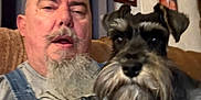 Dolly Sue Herman joined the competition — help win amazing prizes! man, dog, schnauzer, beard, mustache, overalls, couch, indoor, portrait, pet, home, curtain, framed_photos, casual, blurred, relaxed, face, furniture, companion, seated