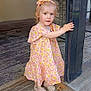 child, toddler, girl, floral_dress, headband, shoes, wooden_floor, post, hand, curly_hair, pink, yellow, pattern, standing, indoor, portrait, cute, small, person, summer