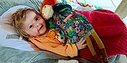 Ambre a rejoint le concours — aidez-le/la à gagner de superbes lots ! baby, child, doll, toy, blanket, seat, cushion, floor, tile, indoor, person, clothing, pacifier, smile, hair, face, comfort, playtime, colorful, relaxation