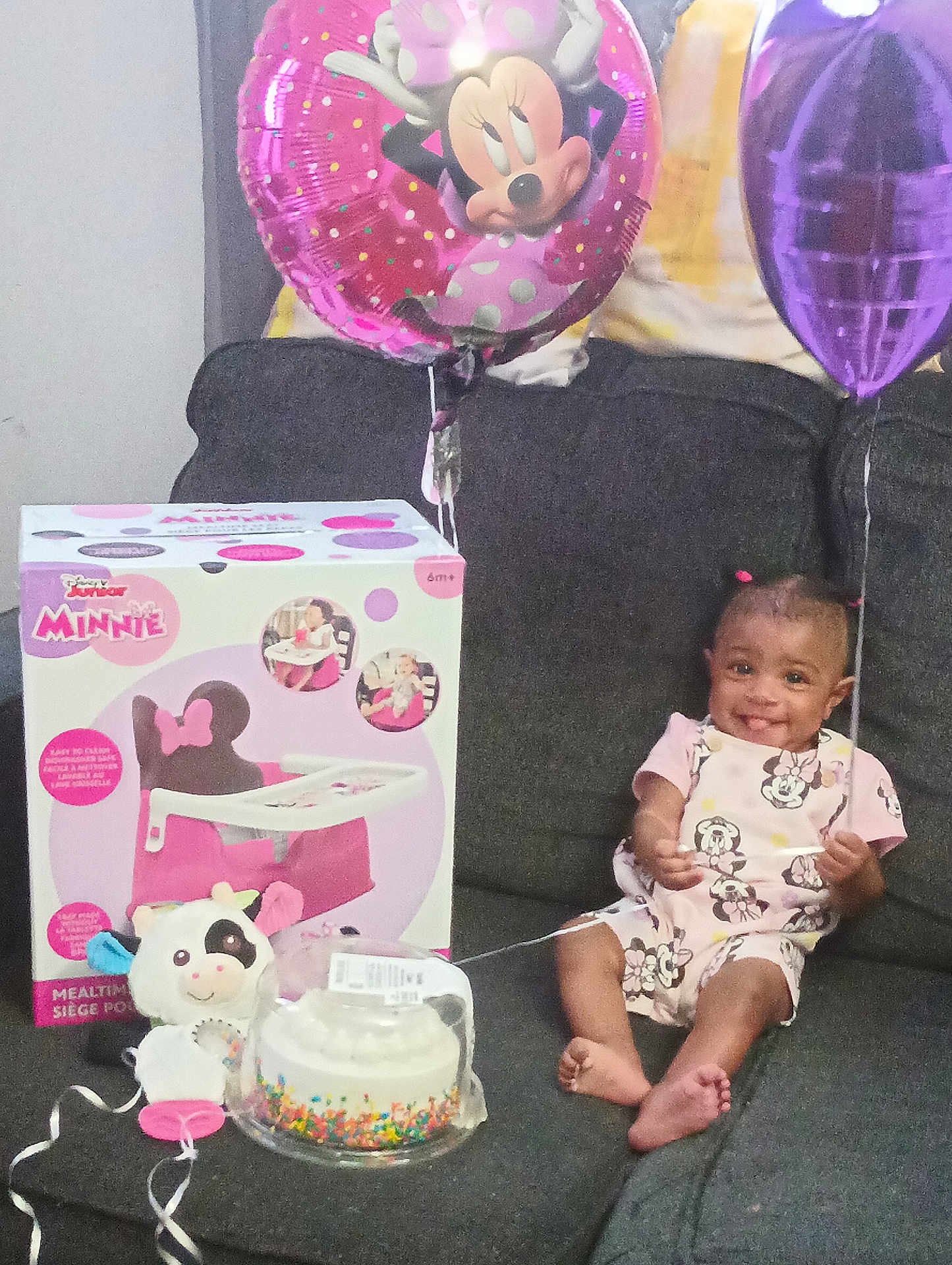 Eri'Yan is registered to the contest to win money with this photo: balloon, birthday_cake, celebration, child, clothing, couch, face, feet, gift_box, hair, happy, indoors, minnie_mouse, party, person, pink, purple, smiling, toddler, toy