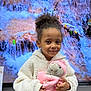 Maya a rejoint le concours — aidez-le/la à gagner de superbes lots ! child, girl, curly_hair, smile, stuffed_animal, pink_clothing, white_jacket, toy, indoor, television_screen, waterfall_image, nature_background, portrait, cute, happy, holding, clothing, face, person, young