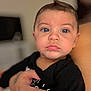 Matheo is registered to the contest to win money with this photo: baby, child, face, blue_eyes, black_clothing, hand, tattoo, close_up, portrait, indoor, person, cute, expression, skin, holding, young_child, infant, people, focus, blurred_background