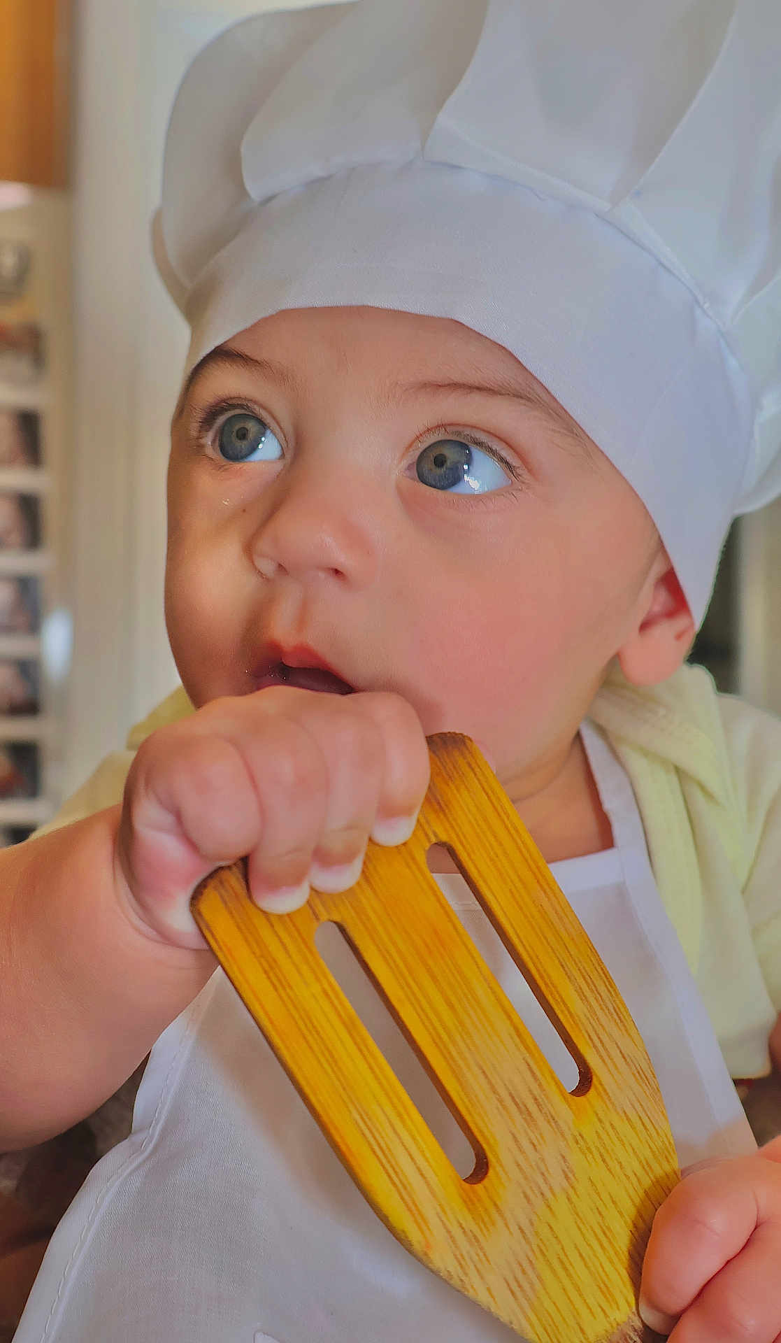 Matheo joined the competition — help win amazing prizes! baby, child, chef_hat, wooden_spatula, apron, blue_eyes, curious, indoor, kitchen, cooking, hand, face, portrait, cute, infant, person, clothing, closeup, expression, young