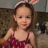 Chloe is registered to the contest to win money with this photo: child, girl, headband, dress, bandage, knee, kitchen, counter, tiles, smile, socks, hair, cute, indoor, person, young, playful, background, accessory, pose