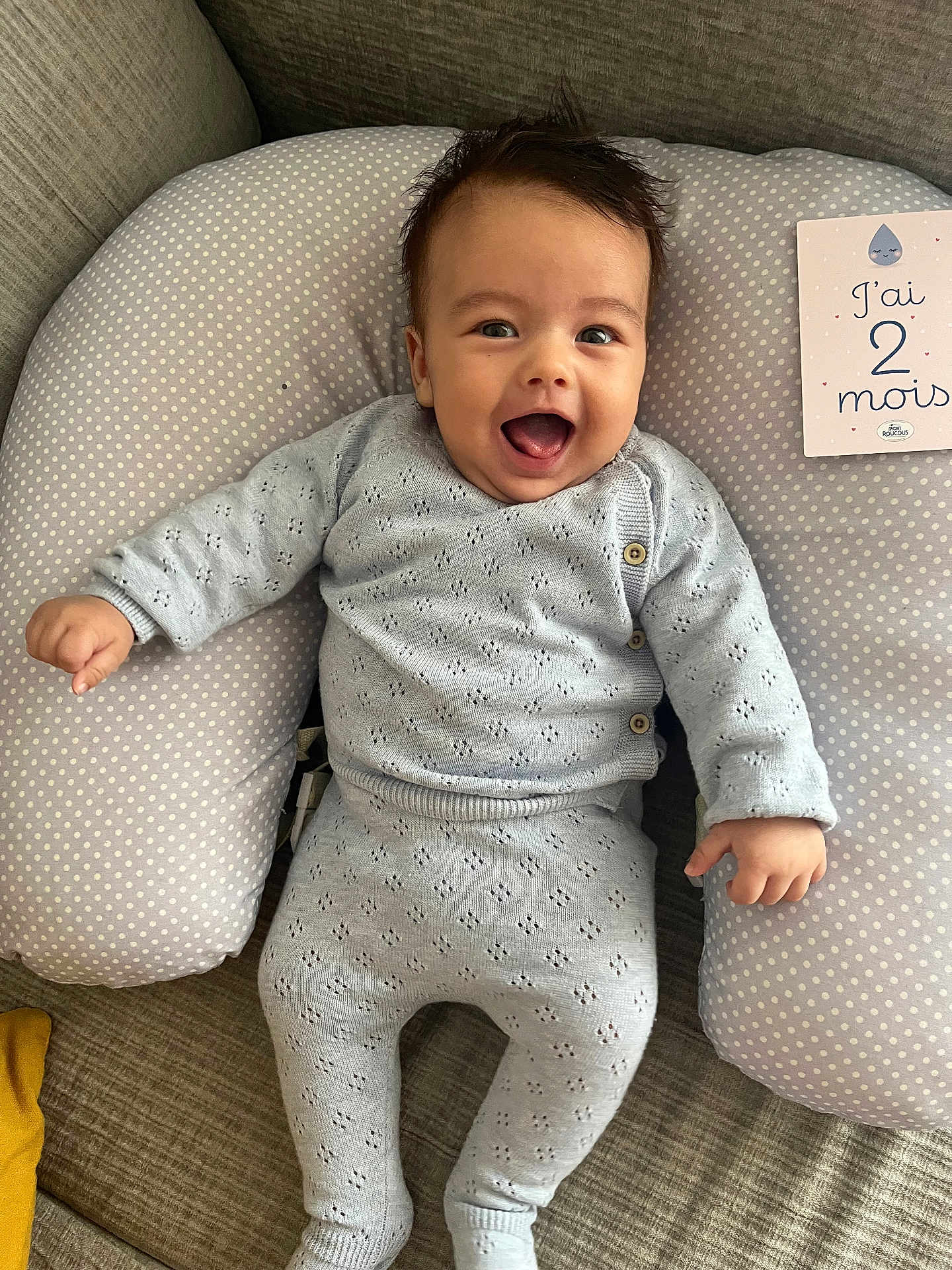 Hédi a rejoint le concours — aidez-le/la à gagner de superbes lots ! baby, smiling, infant, knitwear, cushion, polka_dot, milestone_card, indoor, happy, sitting, face, person, cozy, couch, cute, child, clothing, portrait, home, celebration