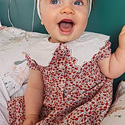 Giulia participe au concours pour gagner de l'argent avec cette photo : baby, child, smiling, blue_eyes, white_bow, headband, floral_dress, sitting, bed, pillow, collar, happy, portrait, indoor, cute, infant, cheerful, skin, person, young