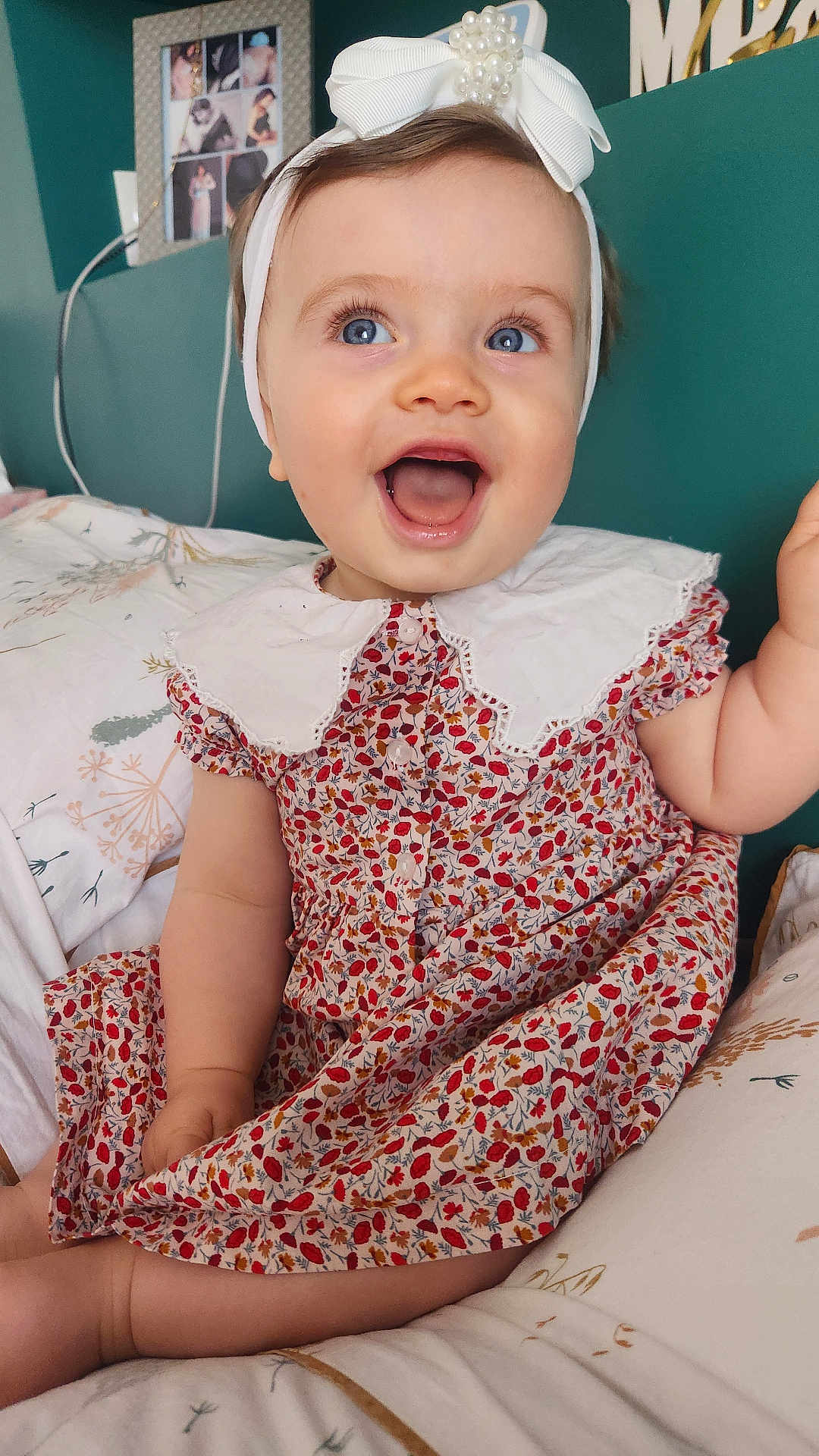 Giulia participe au concours pour gagner de l'argent avec cette photo : baby, child, smiling, blue_eyes, white_bow, headband, floral_dress, sitting, bed, pillow, collar, happy, portrait, indoor, cute, infant, cheerful, skin, person, young