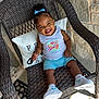 Rhemi joined the competition — help win amazing prizes! blue_bow, blue_shorts, casual_clothing, chair, child, concrete_floor, curly_hair, door, happy, mat, outdoor, pillow, portrait, smiling, sneakers, stone_wall, sunlight, toddler, white_tank_top, woven_chair