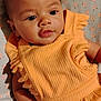 Jayla joined the competition — help win amazing prizes! baby, infant, child, orange_dress, clothing, cute, portrait, face, eyes, hand, skin, lying_down, fabric, pattern, floral, blanket, soft, expression, indoors, person