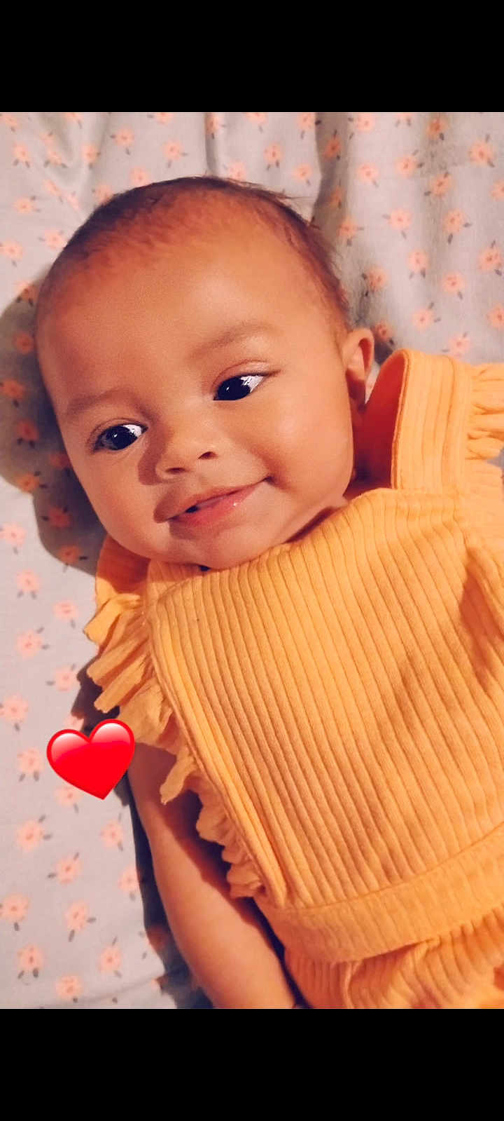 Jayla is registered to the contest to win money with this photo: baby, infant, smiling, orange_clothing, ruffles, blanket, floral_pattern, heart_emoji, cute, portrait, close_up, soft_lighting, happy, child, skin, face, head, lying_down, adorable, infant_girl