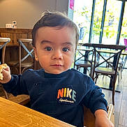Gabriel a rejoint le concours — aidez-le/la à gagner de superbes lots ! toddler, child, indoor, table, bread, clothing, sweatshirt, nike, person, face, eyes, hair, wooden_chair, window, natural_light, cafe, furniture, hand, curious, seated