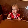 Athena joined the competition — help win amazing prizes! toddler, child, red_dress, smile, table, brown, indoor, person, short_hair, cute, happy, furniture, seat, booth, face, hands, skin, young_child, curious, portrait