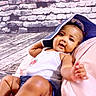 baby, child, smiling, hat, blue_hat, white_tank_top, denim_shorts, brick_wall, wooden_floor, indoor, cute, happy, reaching_hand, portrait, infant, playful, relaxed, skin, person, clothing