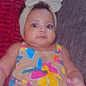 Naziya is registered to the contest to win money with this photo: baby, child, headband, bow, romper, colorful_clothing, couch, pillow, indoor, portrait, smiling, curious, infant, cute, person, skin, face, eyes, hand, seated