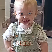 Roxas is registered to the contest to win money with this photo: toddler, child, smiling, indoor, overalls, light_hair, blue_eyes, striped_shirt, furniture, cabinet, wooden, floor, cute, happy, person, portrait, clothing, baby, standing, young_child