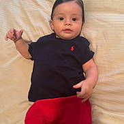 Nathaniel joined the competition — help win amazing prizes! baby, infant, child, person, lying_down, clothing, shorts, shirt, bed, blanket, indoor, cute, face, head, skin, foot, hand, expression, curious, young