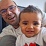 baby, child, man, adult, smiling, glasses, white_shirt, minnie_mouse, portrait, indoor, happy, family, closeup, casual, person, cute, face, people, baby_clothing, tshirt