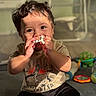 toddler, child, toy, chewing, curly_hair, sunlight, indoor, floor, play, cute, smiling, casual_clothing, shorts, tshirt, colorful_toys, baby, happy, person, portrait, young_child
