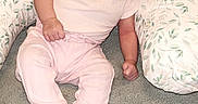Adalynn is registered to the contest to win money with this photo: baby, infant, pink_clothing, socks, pillow, leaf_pattern, carpet, indoors, child, cute, portrait, soft_lighting, seated, young, person, small, curious, head_tilt, cozy, home