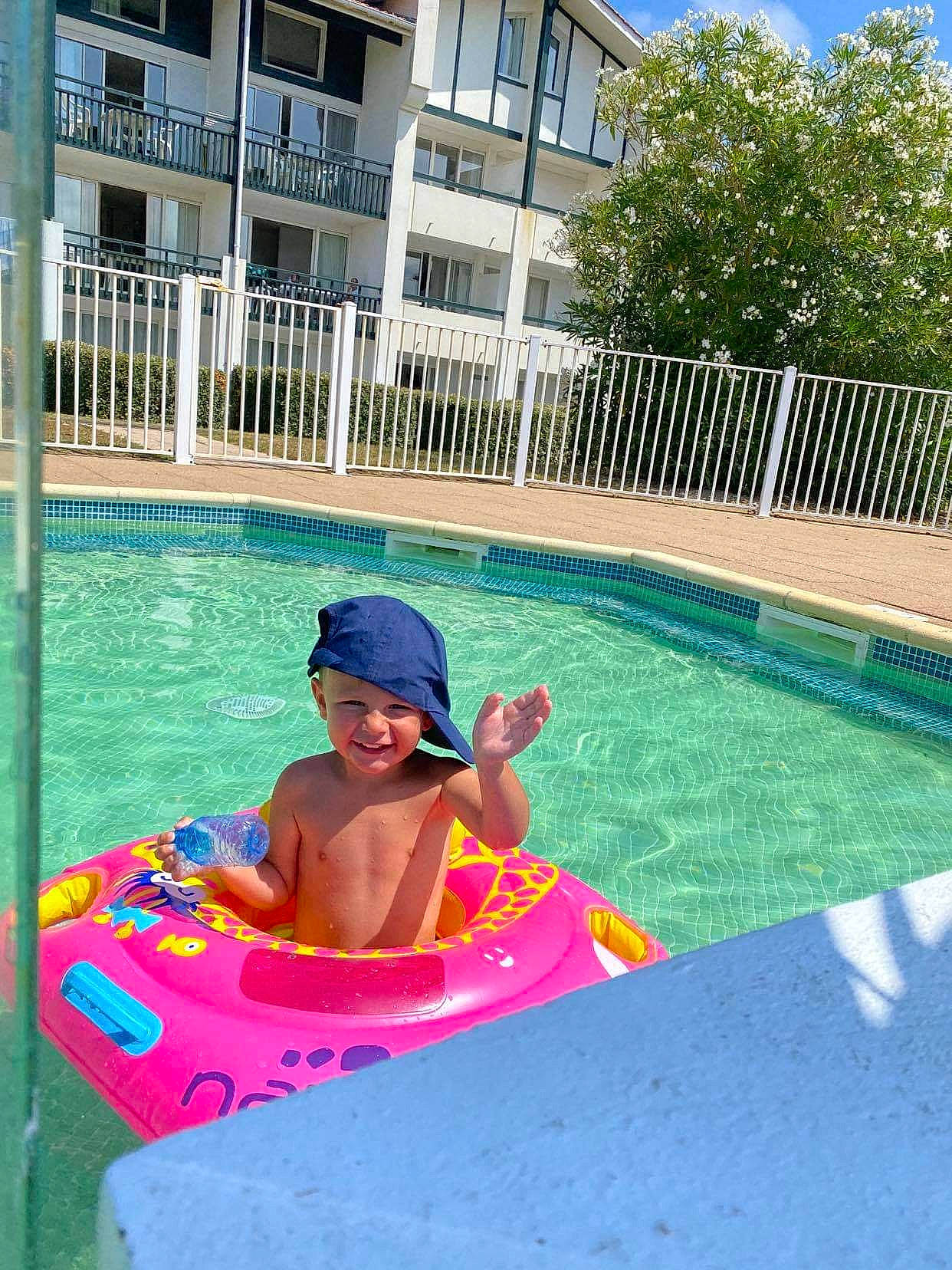 Lorenzo a rejoint le concours — aidez-le/la à gagner de superbes lots ! aqua, baby_float, bathing, building, fence, fun, headwear, house, joy, leisure, outdoor_furniture, person, plant, recreation, sky, smile, summer, swimming_pool, swimwear, toddler