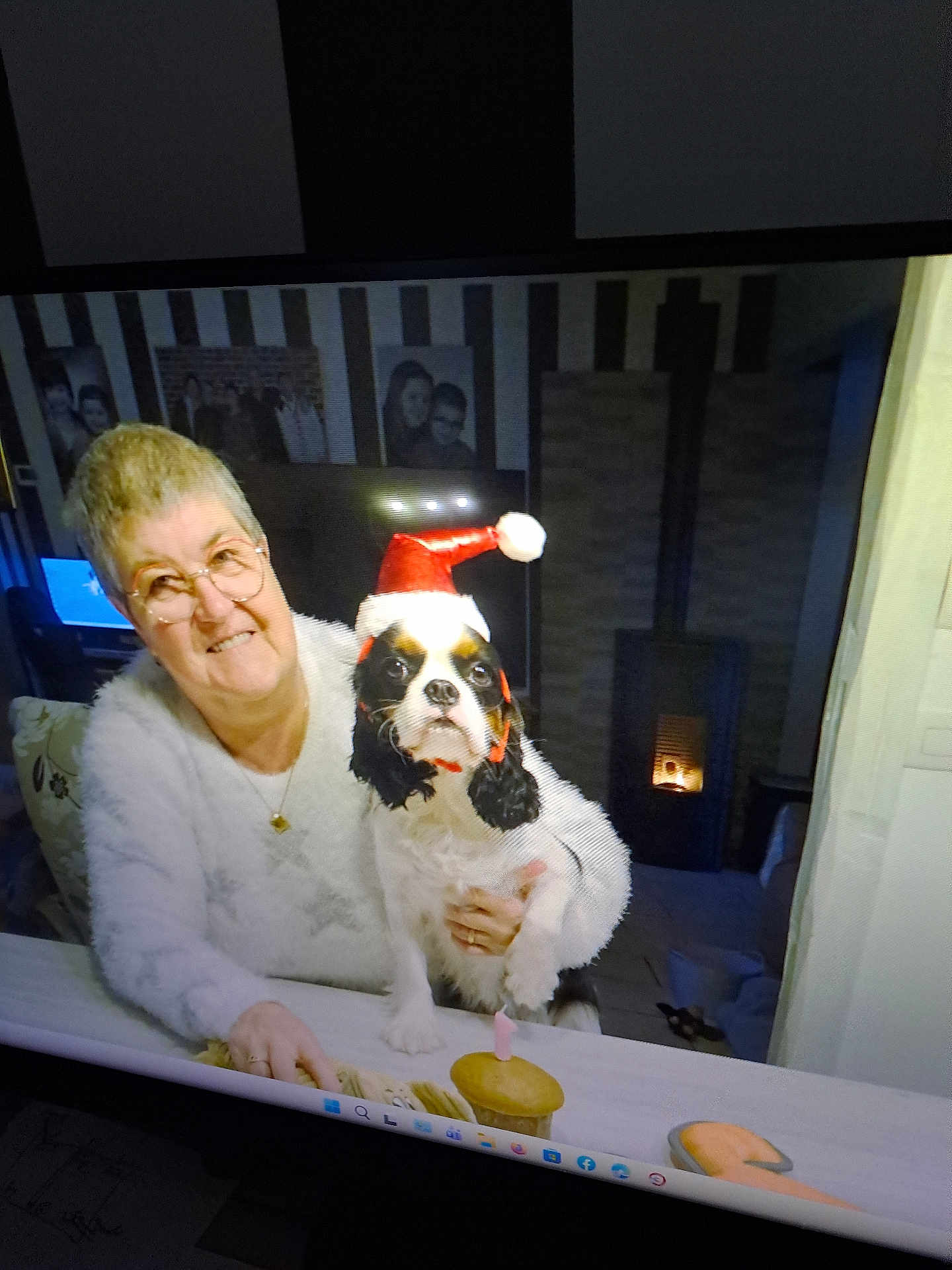 Vyvi participe au concours pour gagner de l'argent avec cette photo : candle, celebration, cozy, cupcake, dog, elderly_woman, family_photos, female, festive, fireplace, glasses, holiday, home_interior, indoor, pet, portrait, santa_hat, smiling, table, white_sweater