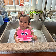 Esme joined the competition — help win amazing prizes! toddler, child, sink, kitchen, water, cleaning_supplies, plant, window_blinds, countertop, faucet, bubbles, foam, curious, indoors, bath, face, person, pink_overlay, heart, expression