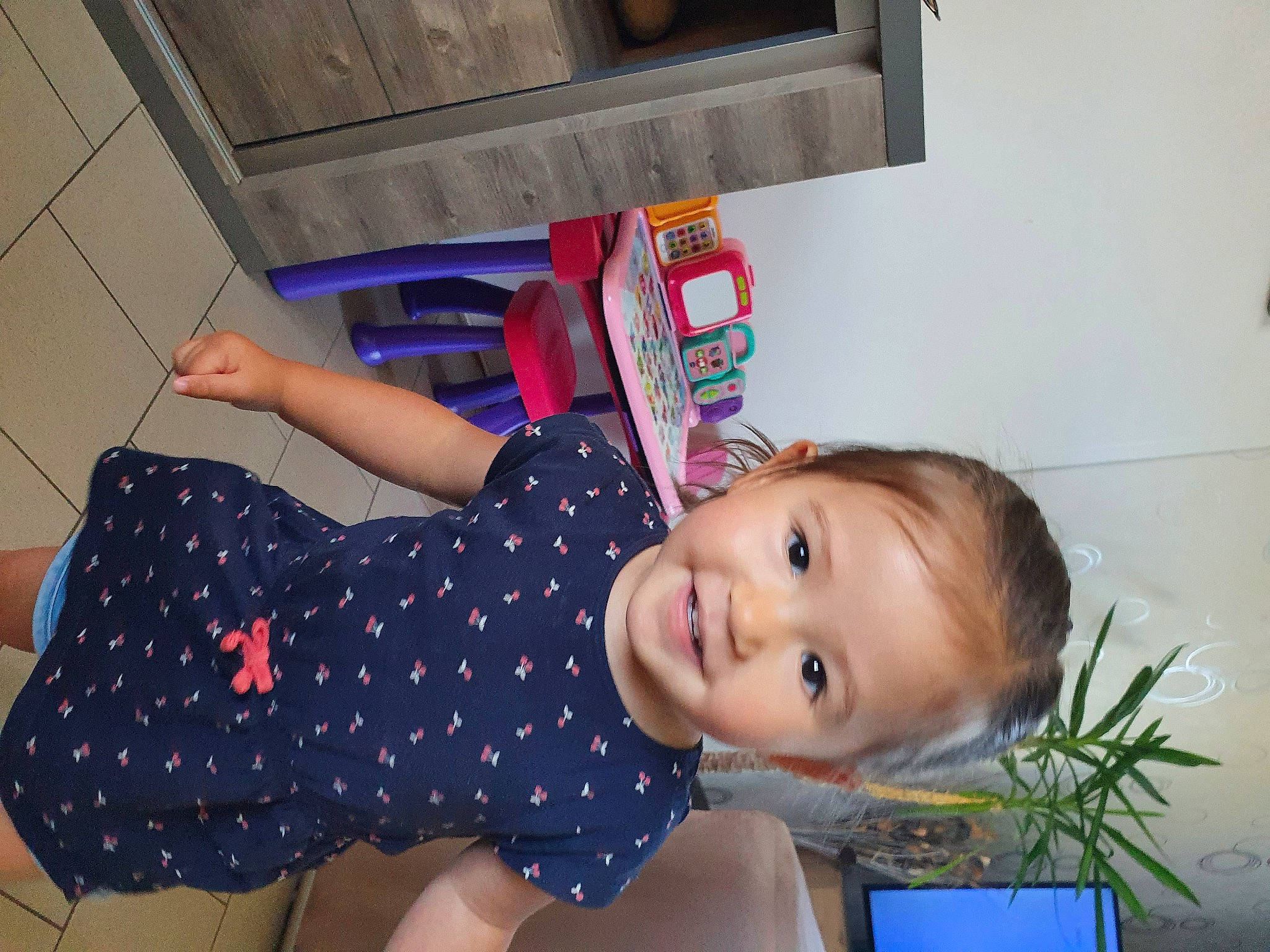 Arya participe au concours pour gagner de l'argent avec cette photo : baby_laughing, baby_toddler_clothing, child, electric_blue, flooring, flowerpot, fun, happy, human_leg, joy, party, pattern, person, plant, play, room, sitting, smile, tableware, thigh