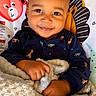 baby, infant, smile, blanket, clothing, face, cute, child, portrait, sitting, animal_print, happy, cozy, indoors, baby_seat, hand, furniture, texture, warm, comfort