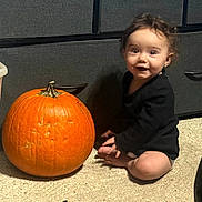 Amanda joined the competition — help win amazing prizes! child, toddler, pumpkin, autumn, halloween, sitting, smiling, portrait, indoor, carpet, kitchen, cabinets, orange, black_clothing, curly_hair, barefoot, happy, seasonal, family_photo, still_life