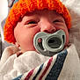 baby, newborn, pacifier, orange_hat, knitted_hat, blanket, striped_blanket, sleepy, close_up, face, infant, cute, cozy, soft, indoors, wrapped, headwear, child, person, portrait