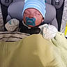 newborn, baby, infant, sleeping, pacifier, car_seat, blue_hat, striped_hat, mittens, blanket, swaddled, portrait, face, closed_eyes, cozy, child, vehicle, safety_seat, indoor, photograph