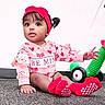 Lulu is registered to the contest to win money with this photo: toddler, child, baby, portrait, sitting, indoor, smiling, red_bow, pink_clothing, hearts, toy_truck, colorful_toy, carpet, playroom, face, eyes, hair, shoes, fashion, cute