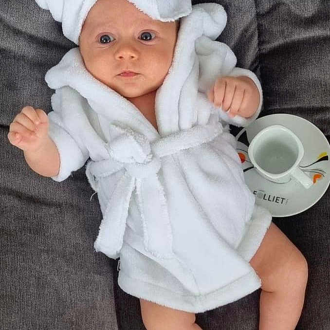 Talya a rejoint le concours — aidez-le/la à gagner de superbes lots ! baby, beverage, blanket, bonnet, clothing, coffee, coffeecup, couch, dress, face, fashion, hat, head, newborn, person, photography, portrait, robe, sitting, towel