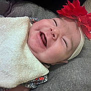 Laseya joined the competition — help win amazing prizes! baby, infant, headband, flower, smiling, happy, face, closeup, bib, clothing, lying_down, patterned_clothes, soft_surface, skin, person, cute, cheerful, indoors, child, portrait