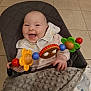 baby, smiling, toy, bib, blanket, seat, happy, child, indoor, floor, person, cushion, colorful, play, infant, cute, hand, clothing, head, face