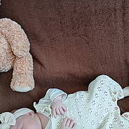Judith participe au concours pour gagner de l'argent avec cette photo : baby, infant, sleeping, blanket, brown, knitwear, headband, teddy_bear, soft_toy, cozy, cute, newborn, child, resting, indoor, person, portrait, clothing, peaceful, comfort