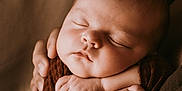 Judith a rejoint le concours — aidez-le/la à gagner de superbes lots ! baby, sleeping, arms, hands, brown_cloth, newborn, peaceful, portrait, closeup, human, infant, skin, soft_light, resting, tender, emotion, care, comfort, warm, cuddle