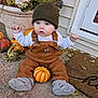 Charlie joined the competition — help win amazing prizes! baby, child, overalls, beanie, pumpkin, fall, autumn, porch, welcome_mat, plants, flowers, curious, sitting, outdoor, seasonal, cute, clothing, person, cozy, harvest