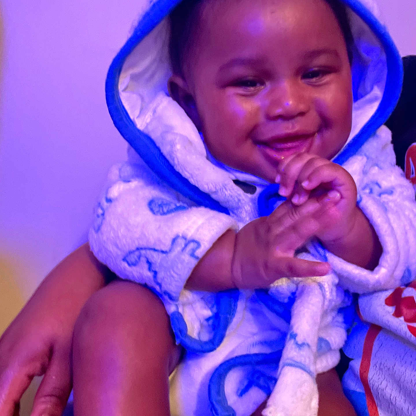 Johnte is registered to the contest to win money with this photo: arm, baby, child, clapping, cozy, cute, expression, face, hand, happy, hooded_towel, indoor, infant, leg, person, purple_light, sitting, skin, smiling, warm