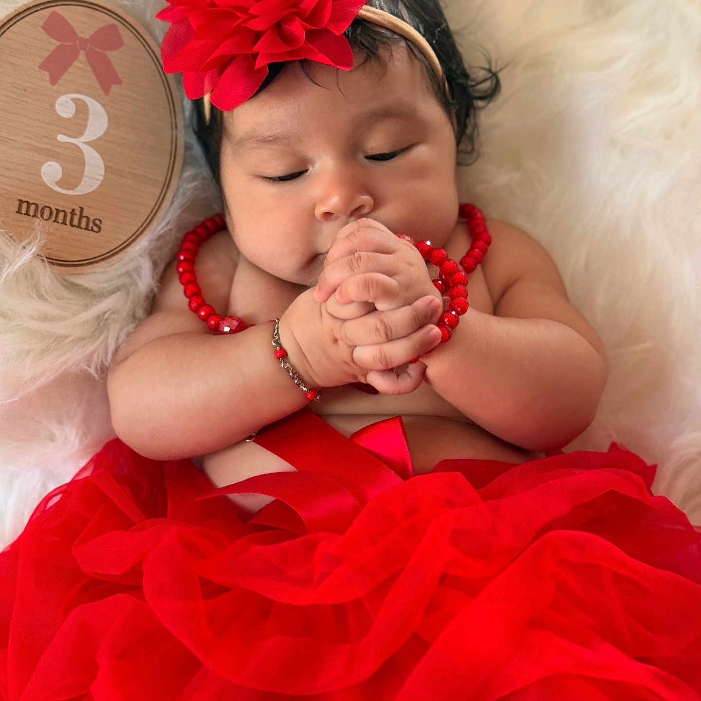 Ahilany Mendoza is registered to the contest to win money with this photo: baby, infant, child, portrait, sleeping, hands, red_flower, headband, red_dress, tutu, necklace, bracelet, fluffy_blanket, white_background, wooden_sign, three_months, close_up, indoor, fashion, cute