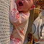 baby, infant, smiling, pink_clothing, ladybug_pattern, blanket, indoor, soft_texture, happy, cute, child, sleepwear, face, newborn, cozy, nursery, lying_down, person, expression, warm_lighting