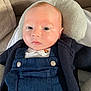 baby, infant, child, face, head, blue_overalls, knitted_sweater, cushion, sofa, indoors, portrait, resting, light_skin, red_hair, young_child, clothing, comfort, close_up, expressionless, casual