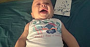 Sacha a rejoint le concours — aidez-le/la à gagner de superbes lots ! 5_mois, baby, blanket, child, clothing, cute, face, happy, indoors, infant, joyful, laughing, lying_down, orange_pants, person, playful, sign, smile, tank_top, wooden_wall