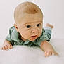 baby, infant, child, face, eyes, hand, arm, green_shirt, lying_down, white_background, soft_texture, curious, expression, skin, portrait, closeup, childhood, crawling, young, person